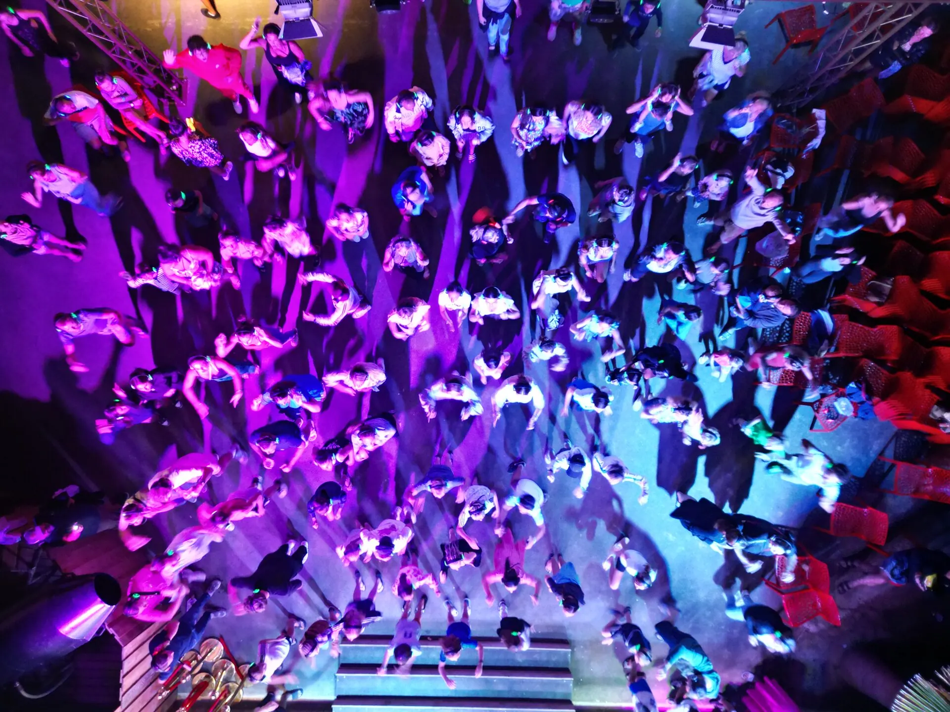 Vue aérienne silent disco extérieur — plusieurs centaines d'invités avec casques lumineux